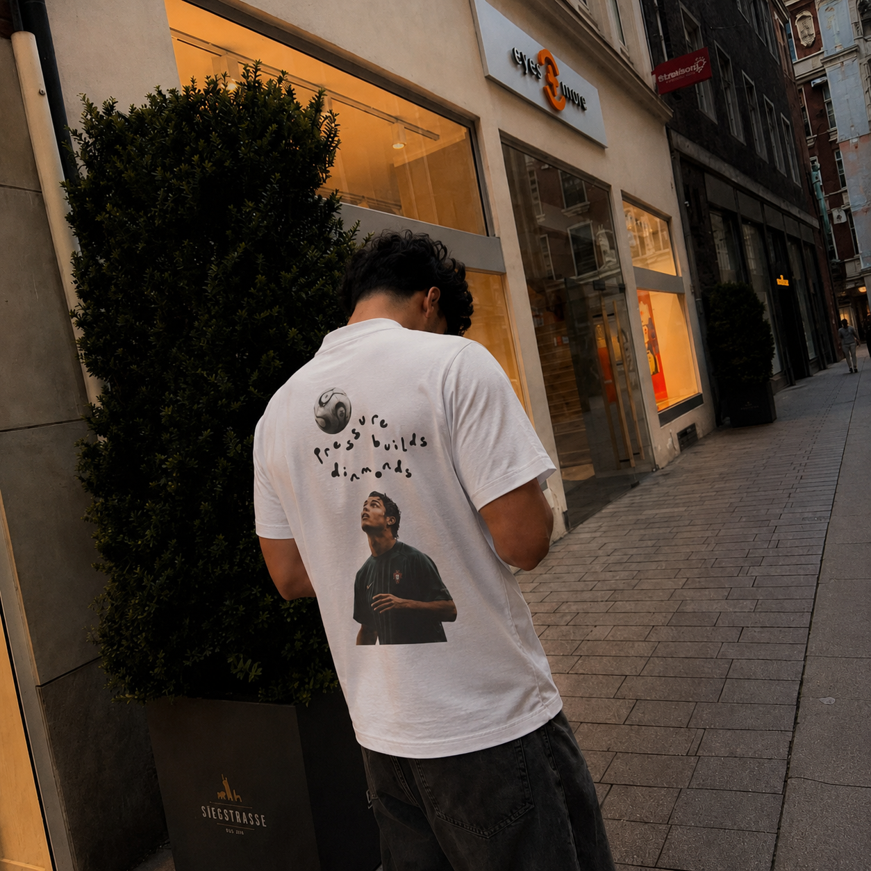 Model wearing the Pressure Builds Diamonds tee on a city street
