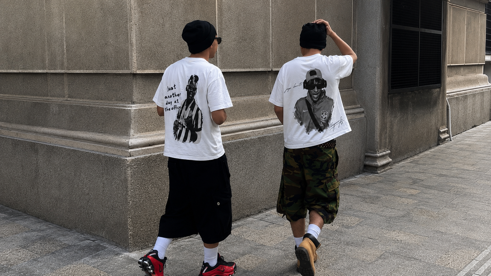 Two friends walking through the city wearing the Day At The Office and Joga Bonito tees