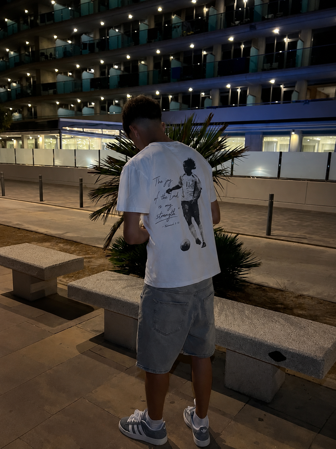 Model wearing the Joy Of The Lord tee at night in front of a hotel