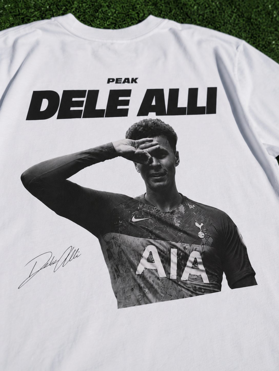 Dele Alli Peak T-shirt in white featuring a black and white football design on artificial turf zoomed in