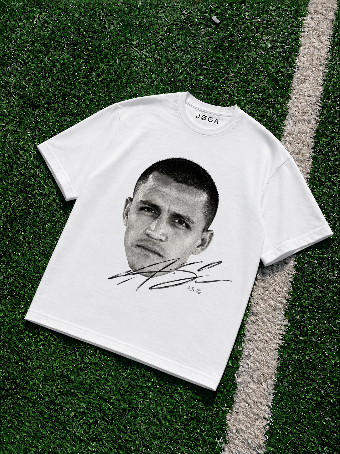 White JOGA oversized T-shirt with a black-and-white Alexis Sánchez face portrait, large signature graphic and A.S. © detailing printed on the front, photographed on green artificial turf.